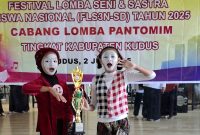 Dua siswa SD 1 Prambatan Lor saat menerima trofi Juara 1 cabang lomba pantomim di FLS3N Kabupaten Kudus Tahun 2025. (Foto: JP)
