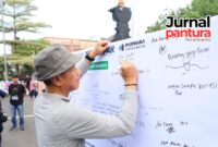 Bupati Kudus Sam’ani Intakoris menandatangani pariwara antikorupsi saat kegiatan sosialisasi antikorupsi yang digelar Inspektorat Kabupaten Kudus di area Car Free Day (CFD), Minggu (24/5). Penandatanganan tersebut menjadi bentuk komitmen Pemkab Kudus dalam mewujudkan pemerintahan yang bersih dan bebas korupsi. (Foto: JP)