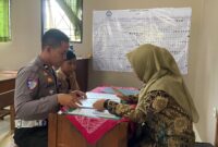 Kanit Gakkum Polres Kudus, Ipda Moh Jafar mengambilkan rapor siswa yatim piatu di SMPN 2 Gebog, Kabupaten Kudus. (Foto: J05)