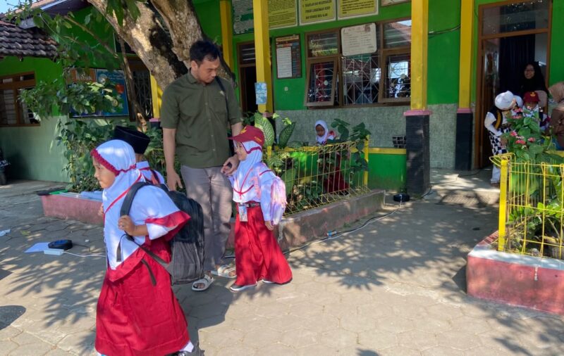 Aris Suryawan (33) mengantarkan putrinya ke sekolah pada hari pertama masuk sekolah tahun ajaran baru 2026/2027 di SD 5 Karangbener, Kabupaten Kudus. (Foto: J05) 